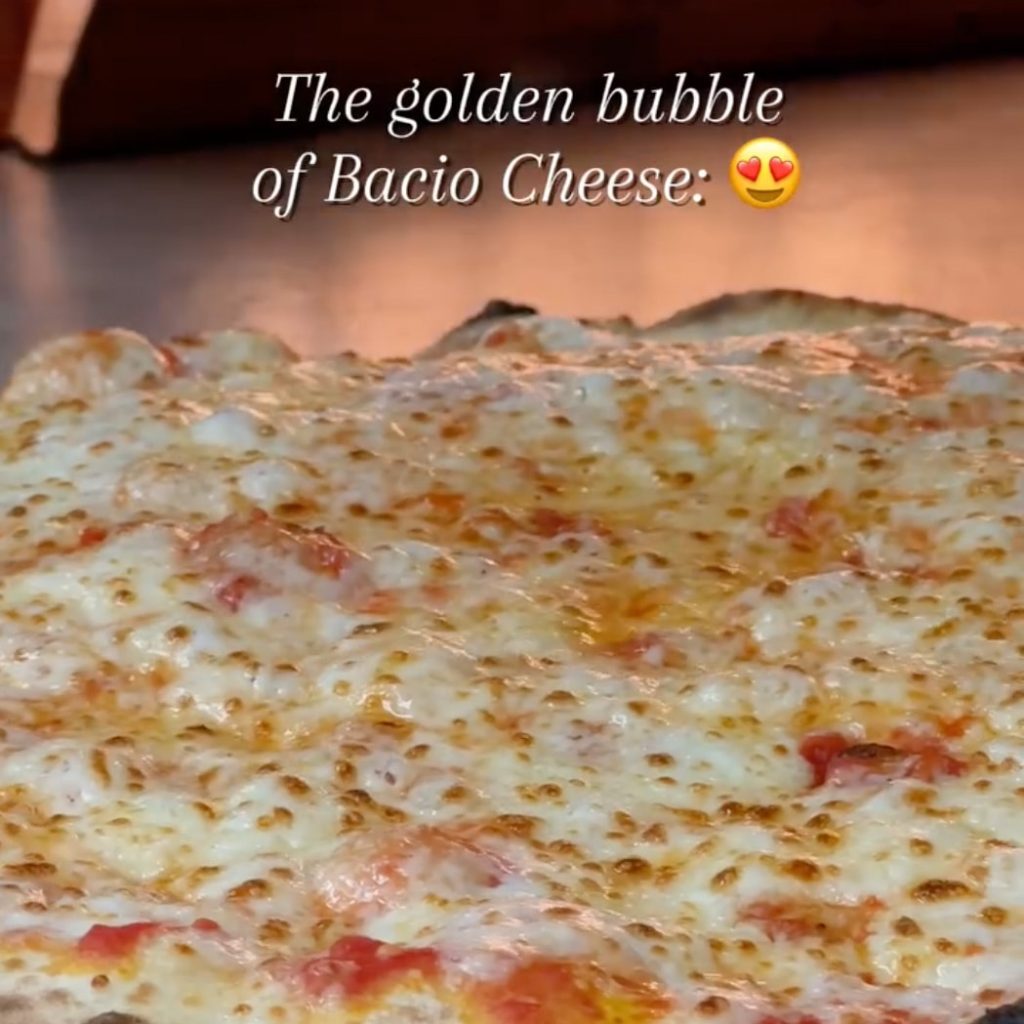 Still from a video showing the bubbling of melting cheese on a hot pizza